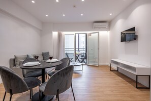 Uma sala de estar moderna com área de jantar, sofá e TV na parede.