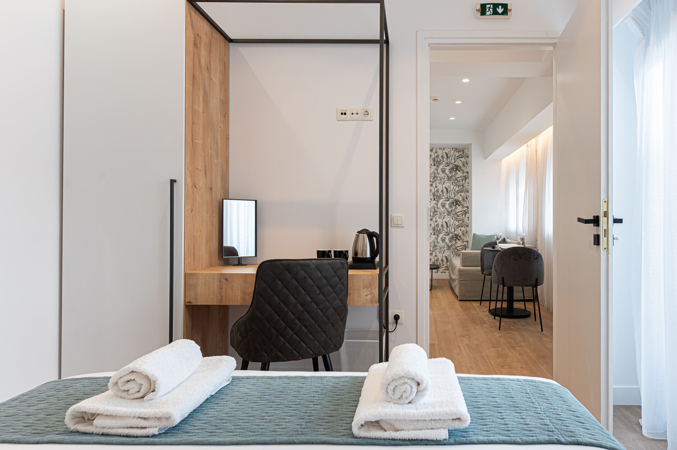 A hotel room with a bed, a desk, a chair, and a small kitchenette.