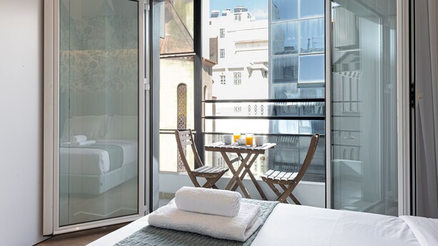 A hotel room with a sliding glass door leading to a balcony with a table and chairs. - Kriel Suites by LIV Homes 201 (Athens)