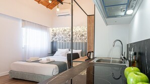 Quarto de hotel moderno com cama, escrivaninha, pia e área de chuveiro.