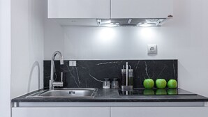 Uma cozinha com pia, torneira e três maçãs verdes no balcão.