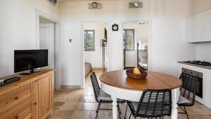 A modern kitchen with a wooden dining table, black chairs, and a TV on a wooden cabinet. - 3686 Villa de Bellis by Perle di Puglia (Fasano)