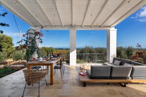 An outdoor patio with a wooden table, chairs, and a sofa. - 3686 Villa de Bellis by Perle di Puglia (Fasano)