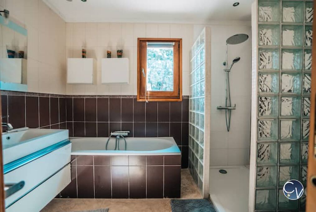 A modern bathroom with a bathtub, a shower, and a window.