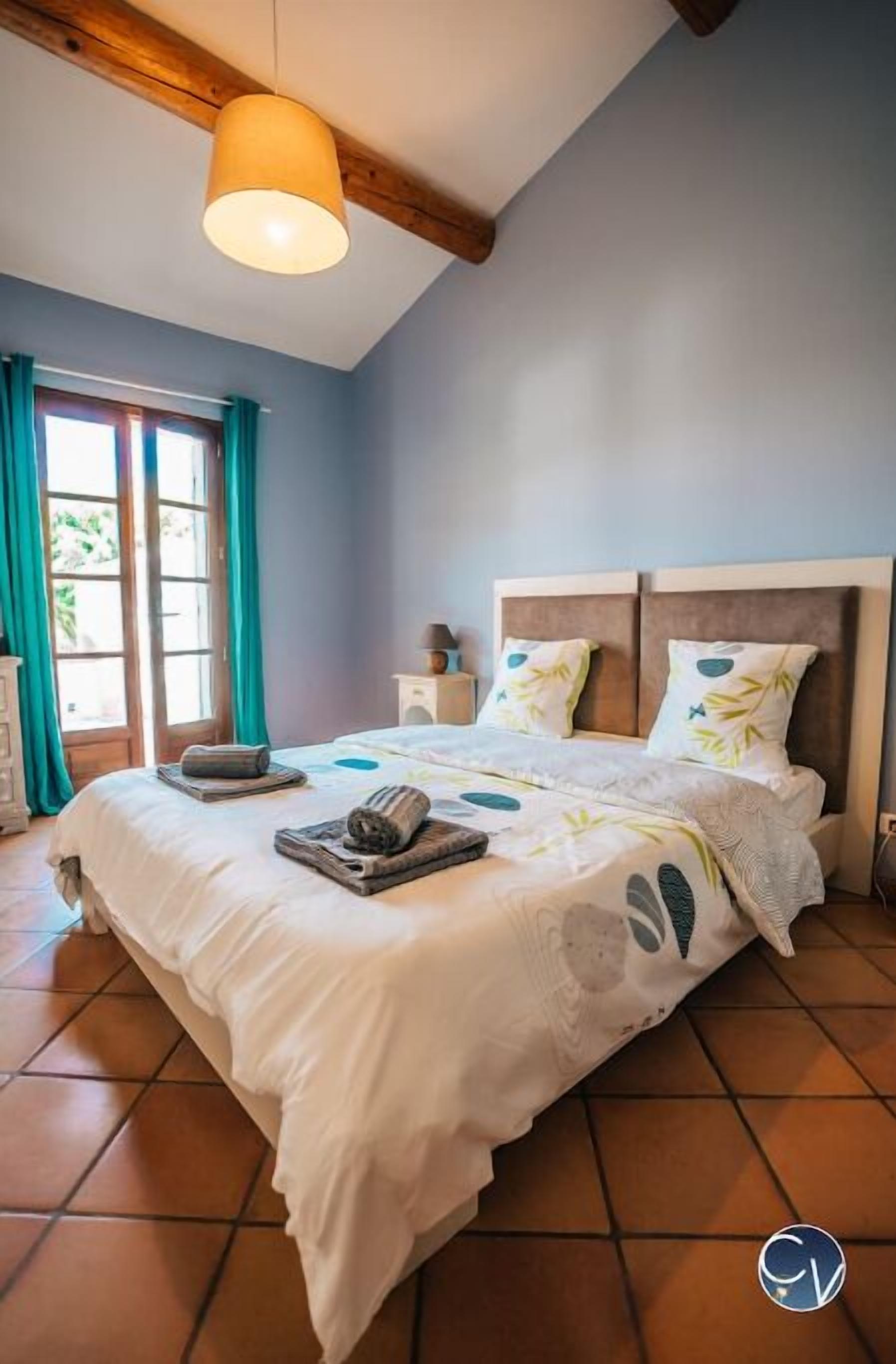 Un dormitorio con una cama grande, una viga de techo de madera y una ventana con cortinas.