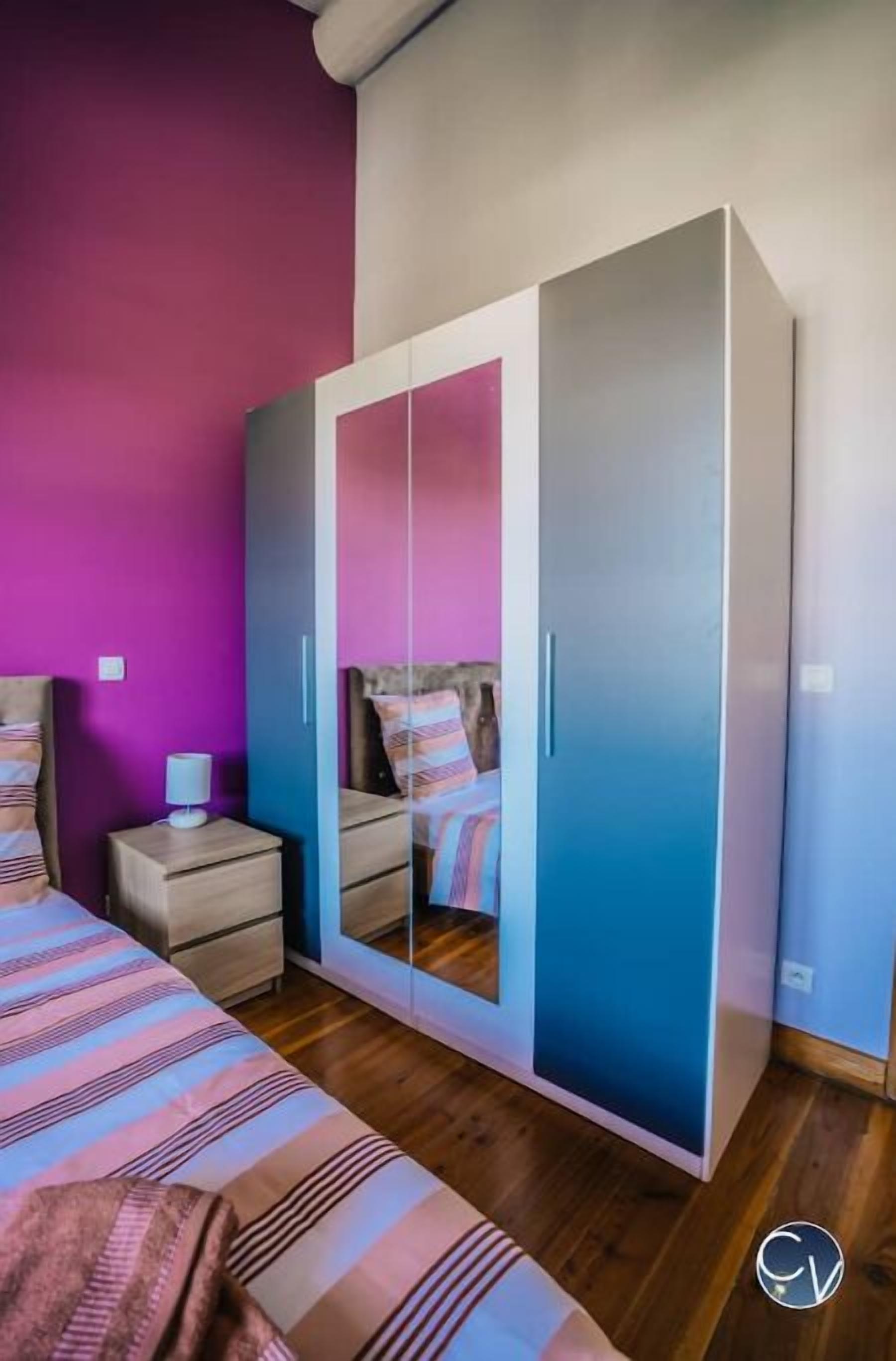 Een slaapkamer met een bed, nachtkastje en kledingkast.