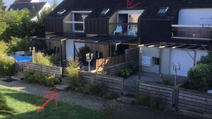 Ett modernt hus i två våningar med ett platt tak, stora fönster och ett väl synligt utomhusområde med en pool.