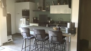 Ett modernt kök med en central köksö, barstolar och en inbyggd ugn.