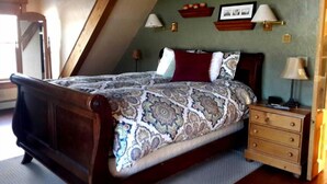 A bedroom with a large bed, wooden headboard, a nightstand with a lamp, and a dresser. - 1882 Bar and Grill at River Street Inn (Truckee)