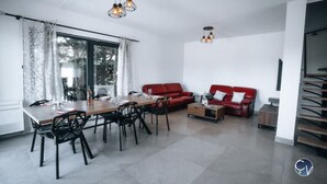 A modern living room with a dining table, red sofas, and a staircase. - Modern villa with Jacuzzi near Avignon (Le Thor)