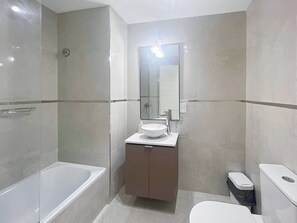 A modern bathroom with a bathtub, a sink with a mirror, and a toilet. - Modern & Cozy Studio in San Telmo w Swimming Pool and Exclusive Services (Buenos Aires)