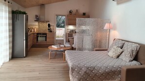 A compact living space with a kitchenette, a sofa, a dining area, and a view of the outdoors. - Petit Paradis Avec Piscine Partagée (Gizay)