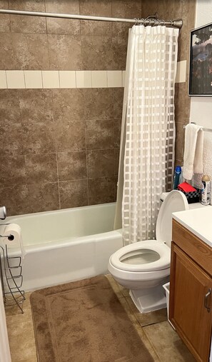 Une salle de bain avec une baignoire, des toilettes et un rideau de douche.