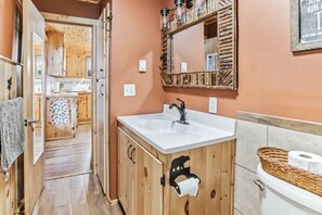 Ein Badezimmer aus Holz mit Waschbecken, Spiegel und Toilette.