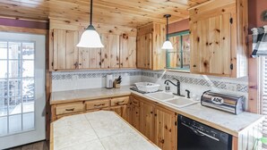 Eine Küche mit Holzausstattung, einem Geschirrspüler, einem Toaster und Pendelleuchten.
