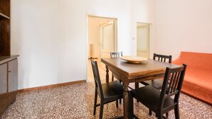A dining area with a wooden table and chairs, a red sofa, and a cabinet. - Lorena Firenze by Mmega (Florence)