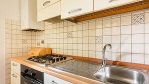 A kitchen with a gas stove, stainless steel sink, and white cabinets. - Lorena Firenze by Mmega (Florence)