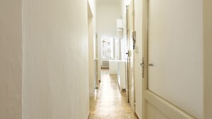 A narrow hallway with white walls and a tiled floor leading to a door at the end. - Lorena Firenze by Mmega (Florence)