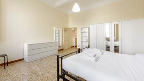 A bedroom with a bed, a wardrobe, a bench, and a door leading to another room. - Lorena Firenze by Mmega (Florence)