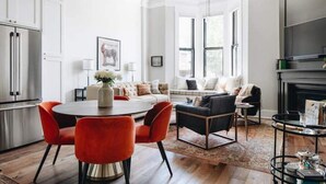 A modern kitchen with white cabinets, a stainless steel refrigerator, and a dining area with a round table and red chairs. - Ulysses Suites, Suite 201, 2 bedroom/2 bath, full kitchen and living room (Galena)