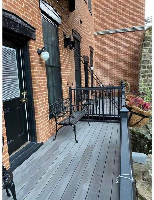 Una terraza de madera con un banco y una barandilla de metal.
