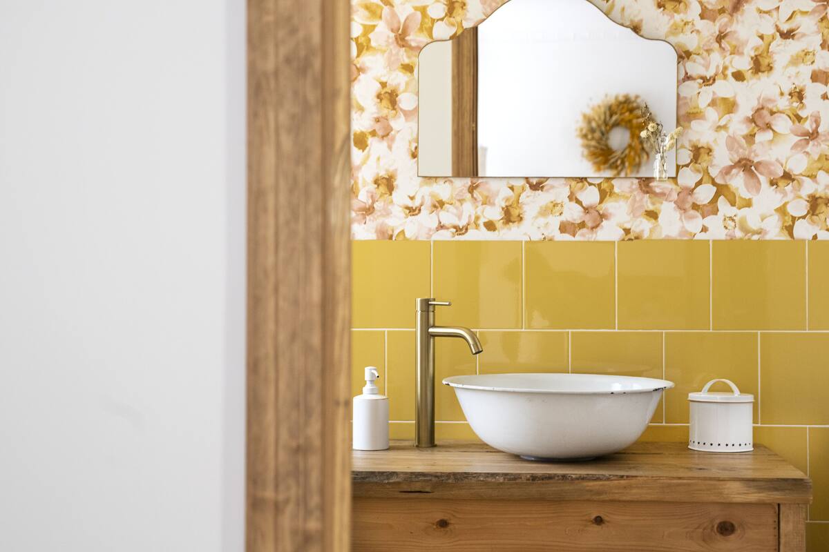 Une salle de bain avec un lavabo blanc, un miroir et des carreaux jaunes.