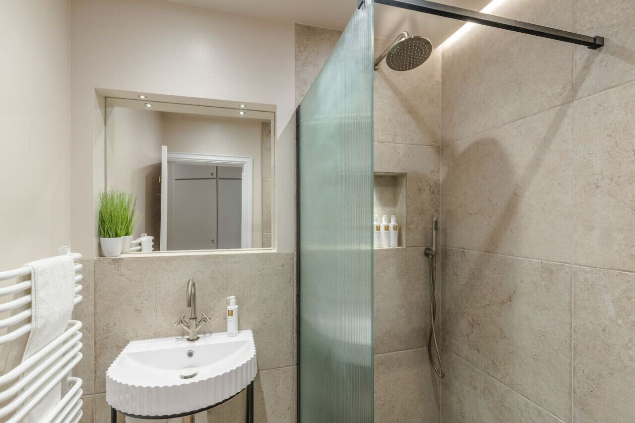 Une salle de bain moderne avec une douche à parois de verre, un lavabo blanc et un miroir au-dessus.