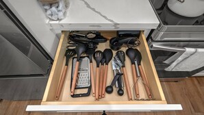A kitchen drawer with various utensils including spatulas, tongs, and a grater. - Island Gems - Gold

 (Galveston)