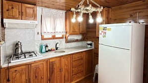 A wooden-paneled kitchen with a gas stove, white refrigerator, and wooden cabinets.