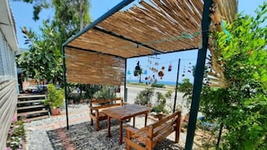 A covered patio area with wooden furniture and a thatched roof.