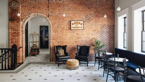 A lobby with a brick wall, a sign reading "ROOMS for TOURISTS", leather chairs, a round ottoman, and a blue sofa. - Ulysses Suites, Suite 203 (Galena)