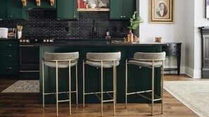 A kitchen with dark green cabinets, a black countertop, and a bar area with stools. - Ulysses Suites, Suite 203 (Galena)