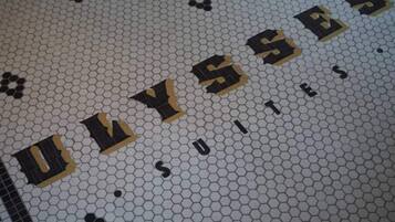 Un sol carrelé sur lequel le mot « ULYSSE » est inscrit en grandes lettres.