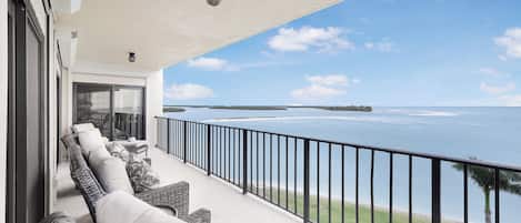 A balcony with outdoor furniture overlooking a body of water.
