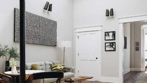 A spacious room with a high ceiling, a dining area with a table and chairs, a sofa, and a large window providing natural light. - Ulysses Suites, Suite 302 (Galena)