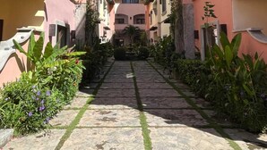 A narrow pathway flanked by buildings with balconies and a clear blue sky above. - Sueño Escondido-West Bay Beach (West Bay)