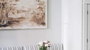 A dining area with a chandelier, a table, chairs, a bench, and a painting on the wall. - Ulysses Suites, Suite 303 (Galena)