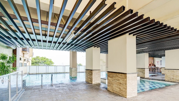 An indoor swimming pool area with a tiled floor, metal railings, and a ceiling with exposed beams. - OYO Life 93310 Apartemen Tamansari Panoramic By Santuy 2 (Bandung)