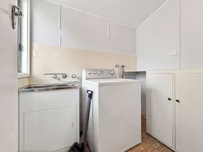 Una cocina funcional con lavamanos, lavadora y armarios.