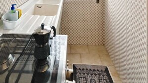 Une cuisine de taille réduite, dotée d’une fenêtre, d’un évier, d’une cuisinière et d’une machine à café.
