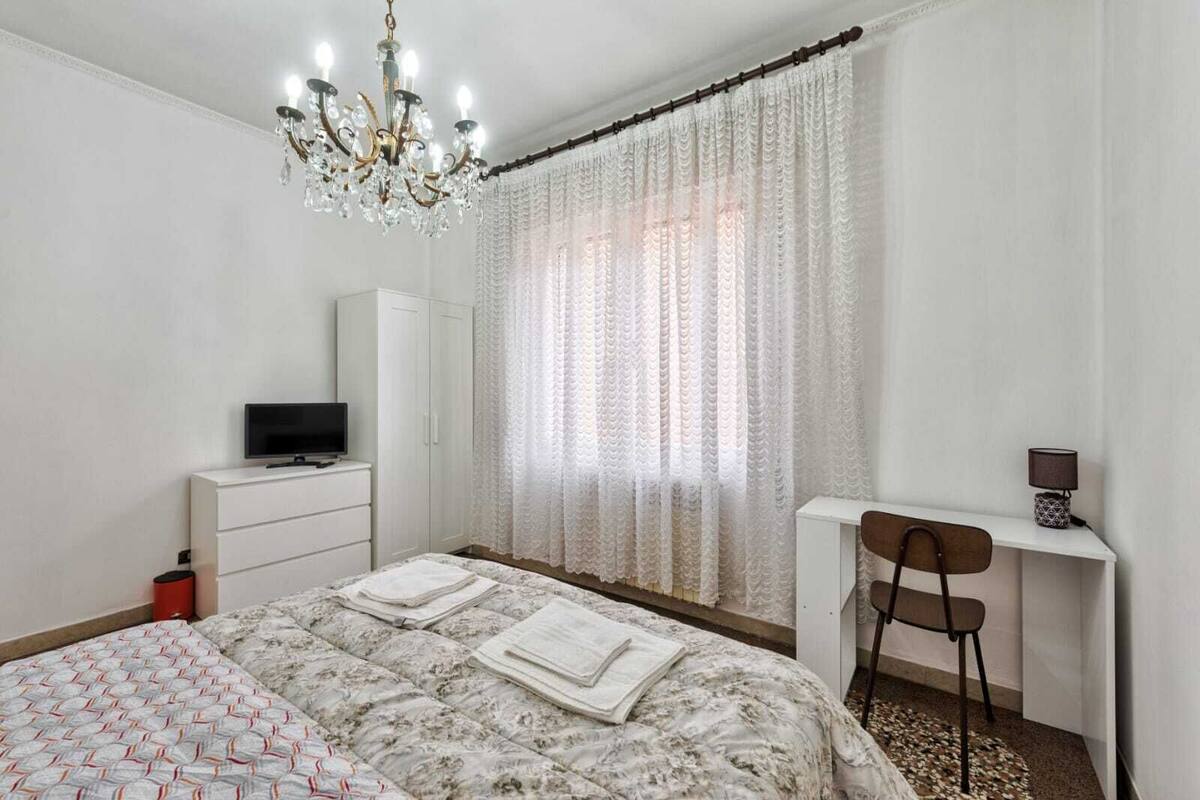 Une chambre à coucher avec un lit, un bureau, une chaise, une télévision et un lustre.