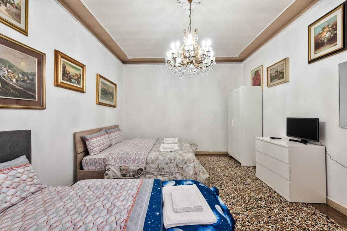 Une chambre avec deux lits, une télévision et une armoire.