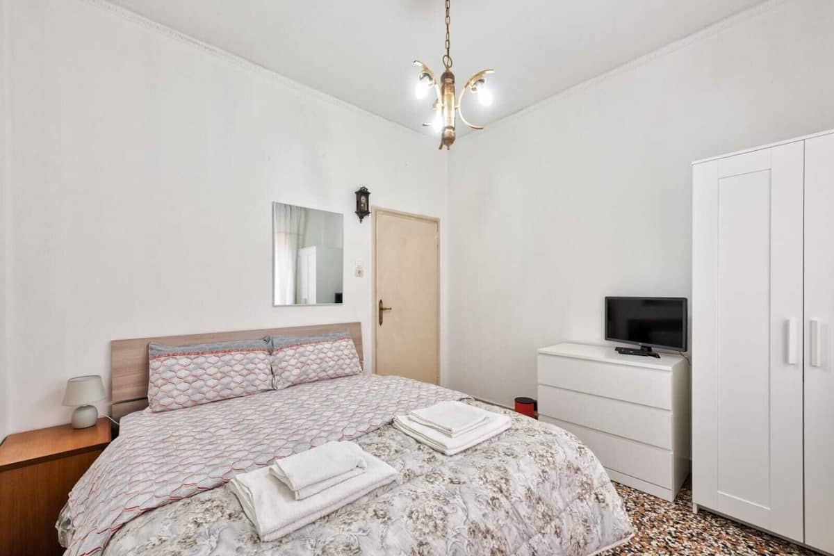 Une chambre à coucher avec un lit, une télévision, une armoire et un miroir.