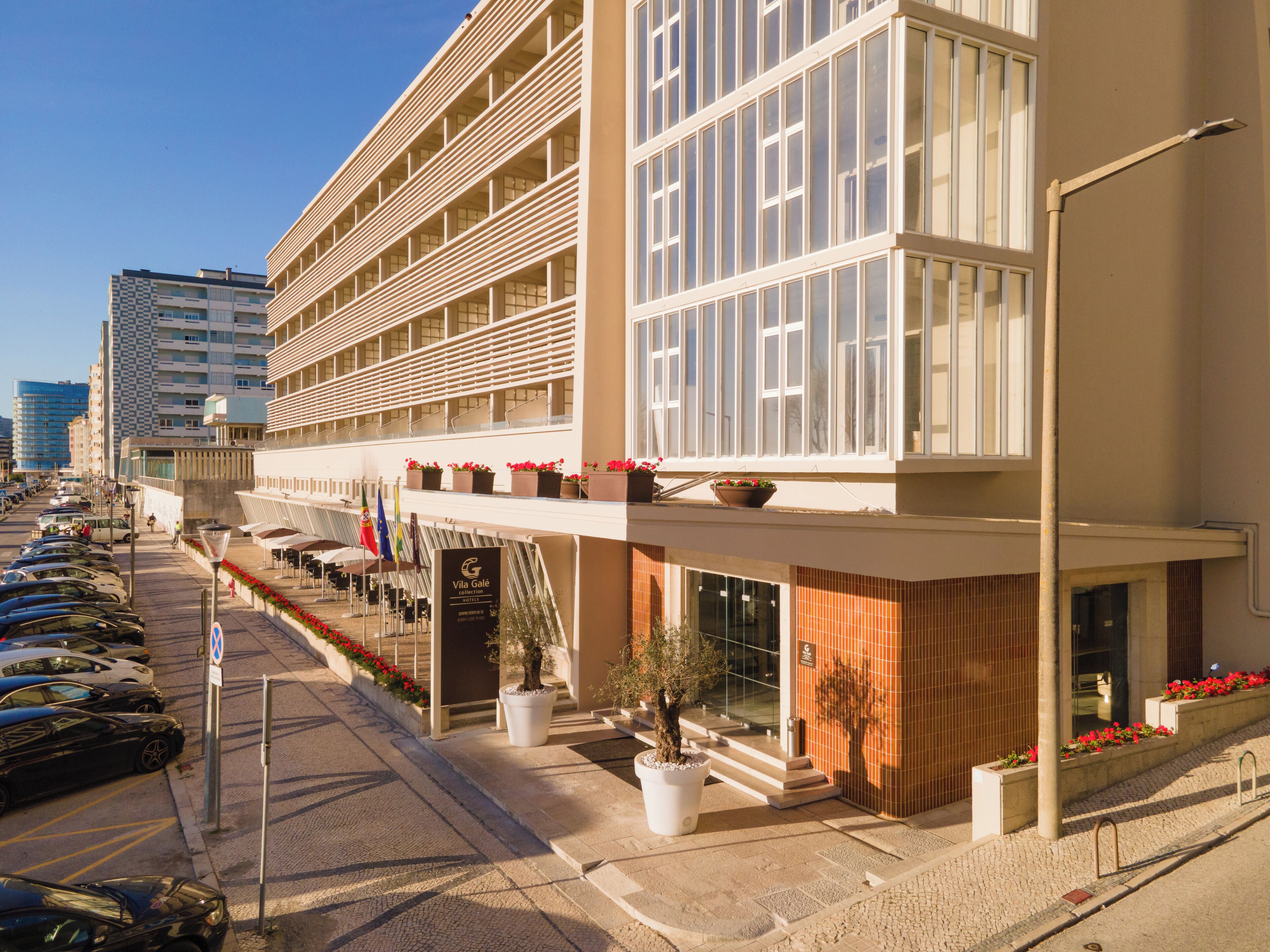 Un hotel moderno con varios balcones, un estacionamiento y vista a la calle.