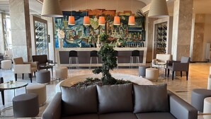 Un hall d’entrée moderne avec un espace salon central, un bar orné d’une fresque murale et un présentoir à bouteilles de vin.