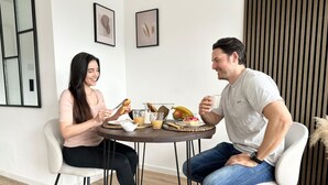 Ein Essbereich mit einem runden Tisch, Stühlen und einer Auswahl an Speisen und Getränken.