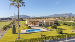 A villa with a swimming pool, surrounded by a well-maintained lawn and vineyard, with mountains in the background. - Els Evols for 6 with pool between Pollensa and Alcudia (Alcúdia)