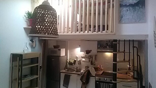 Een kleine keuken met een hanglamp, een kleine koelkast en een fornuis.