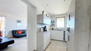 A modern kitchen with white cabinets, a built-in oven, and a window above the sink. - Pretty cocoon with harbour view (Porto-Vecchio)