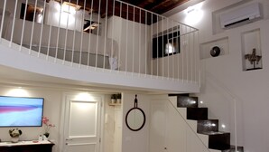 Ein mehrgeschossiges Interieur mit einer Treppe, einem Fernseher und einer Tür.